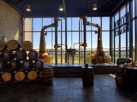 A room filled with barrels and a distillery in the background