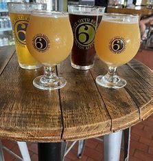 Three glasses of beer are sitting on a wooden table.