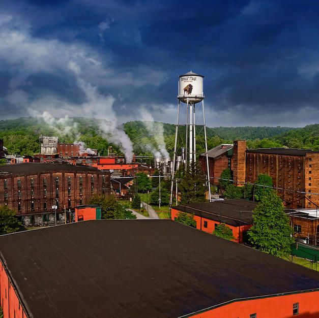 An aerial view of a factory with smoke coming out of it and a water tower.
