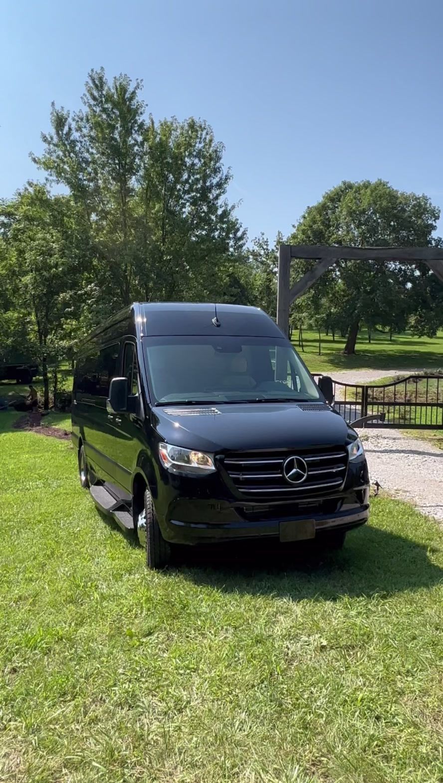 A black van is parked in a grassy field.