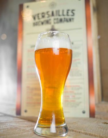 A glass of beer is sitting on a table in front of a sign.