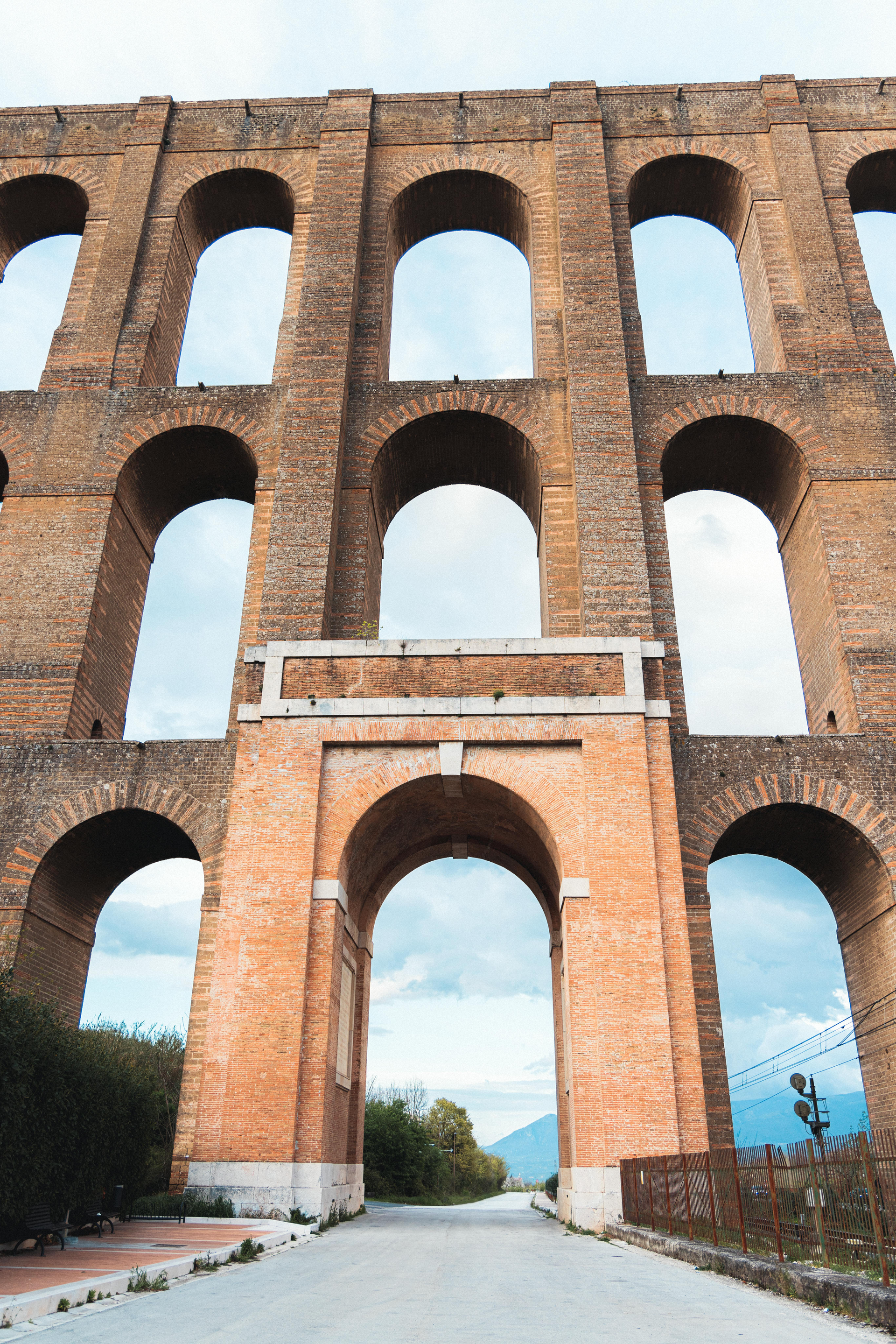 A large brick bridge with arches and a road going underneath it.