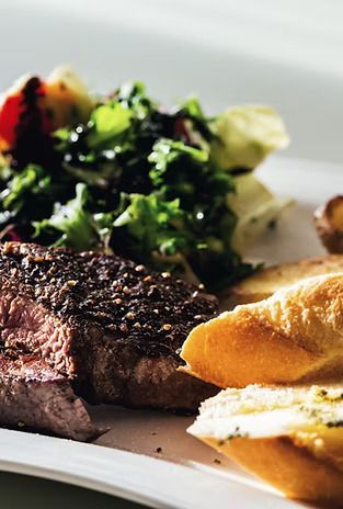 A white plate topped with a steak , salad and french fries.