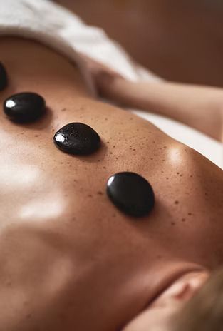 A woman is getting a hot stone massage on her back.