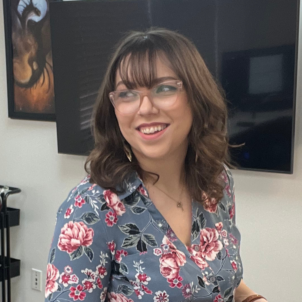 A woman wearing glasses and earrings is smiling for the camera.