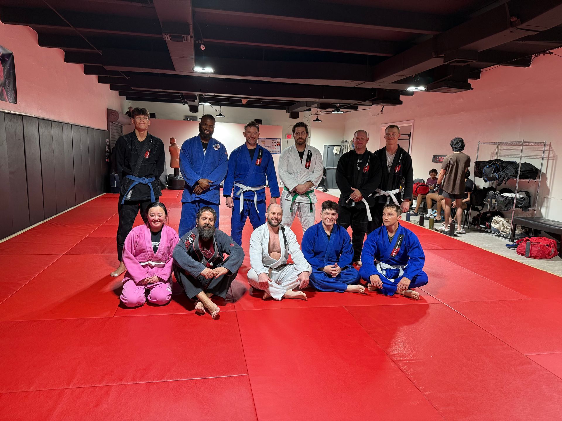 A group of men are sitting on a red mat in a gym.
