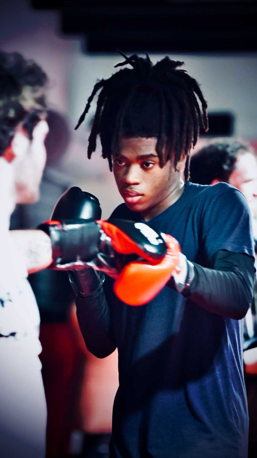 A young man is wearing boxing gloves in a gym.