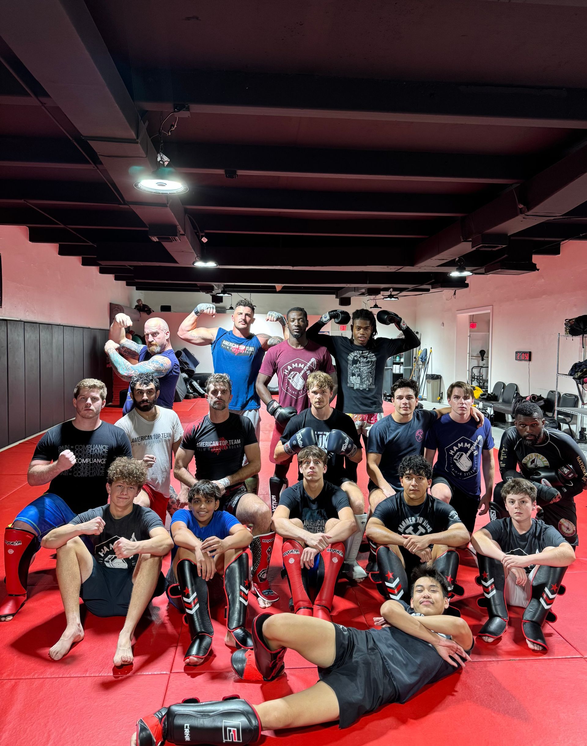 Three men are standing on a wrestling mat and one of them is wearing a yellow belt