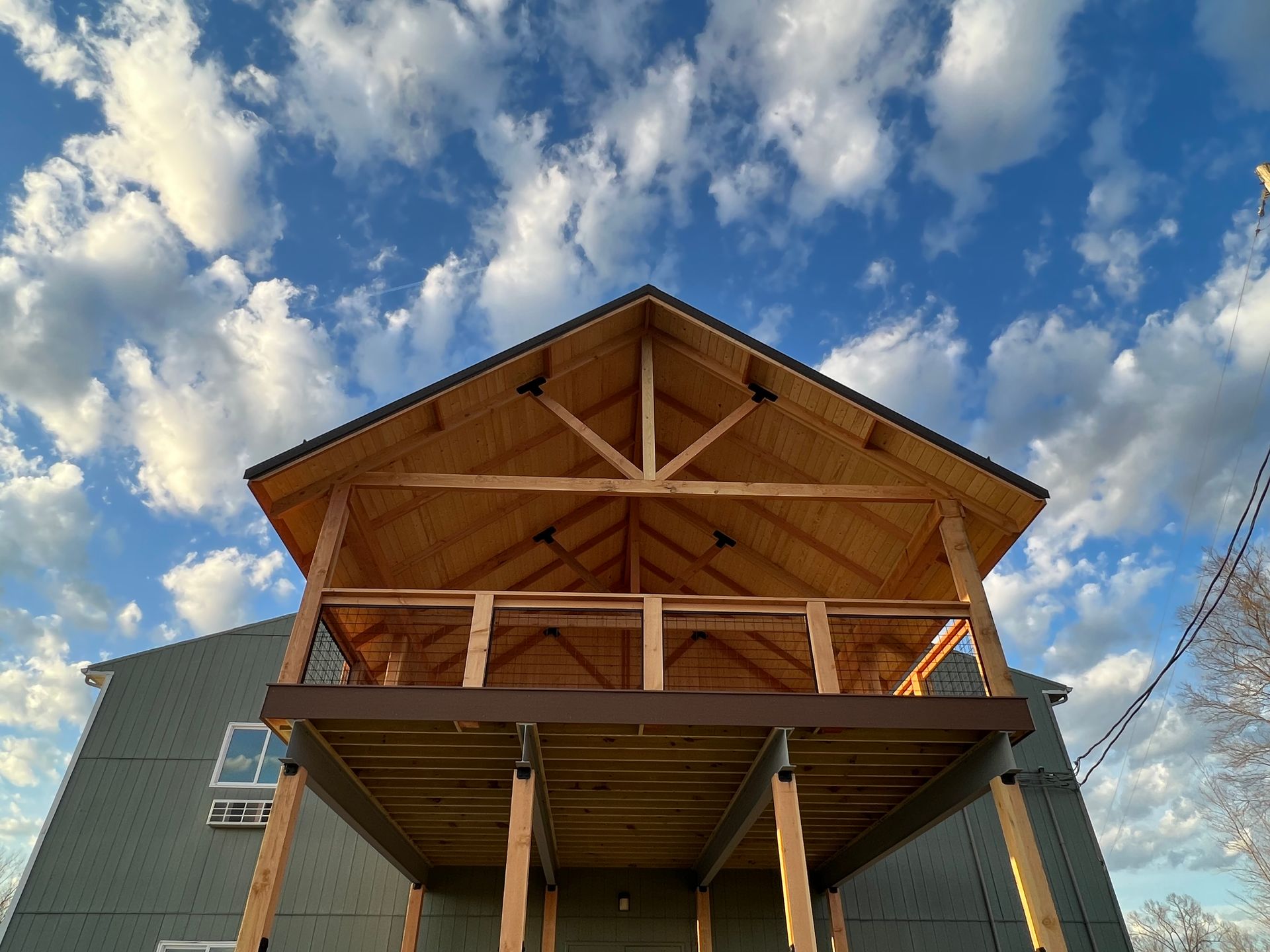 a house with a wooden deck and a blue sky with clouds in the background .