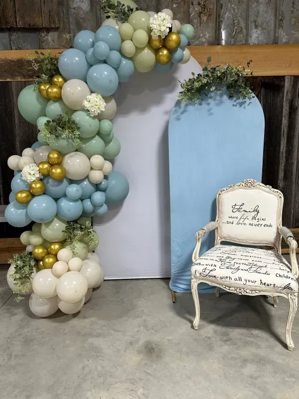 A chair is sitting in front of a balloon arch.
