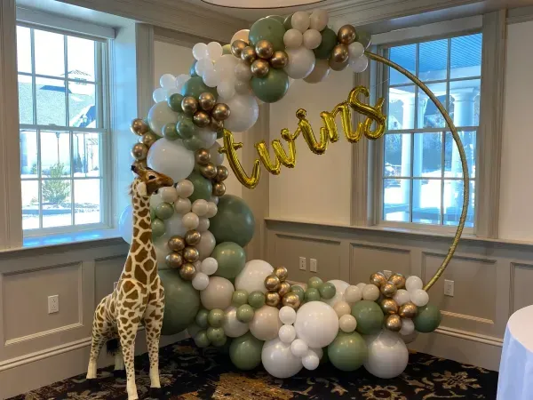 A room decorated with balloons and a stuffed giraffe.