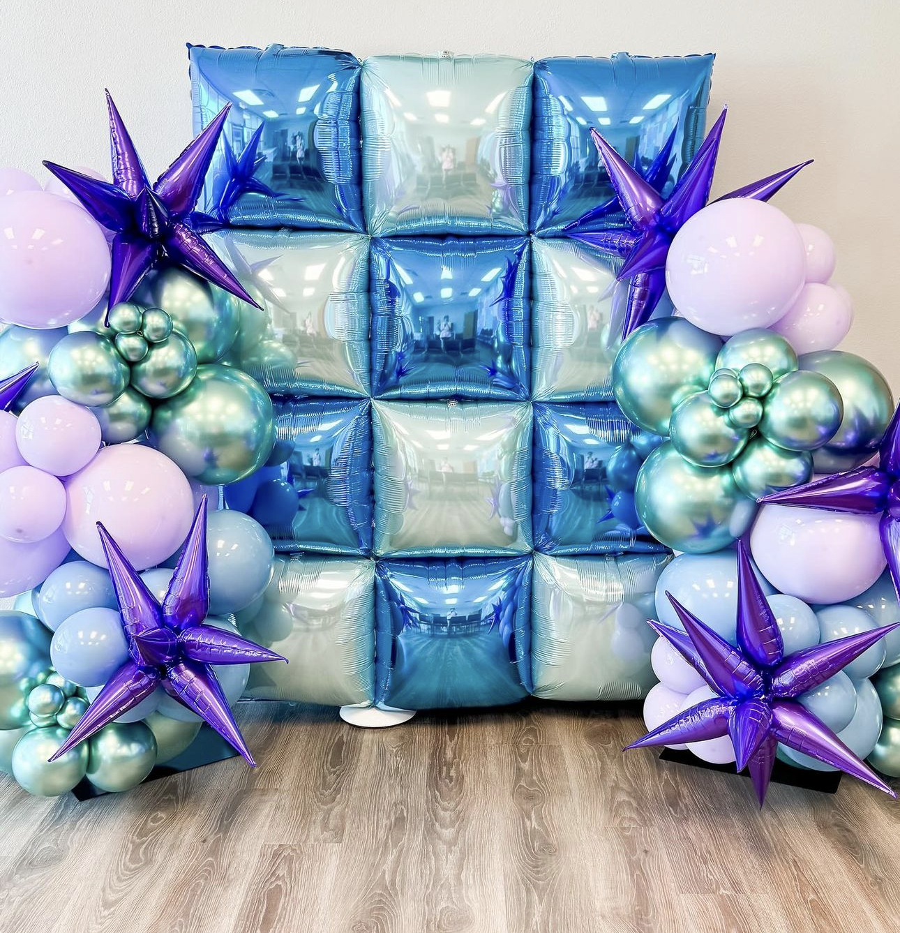 A wall filled with blue and purple balloons and stars.