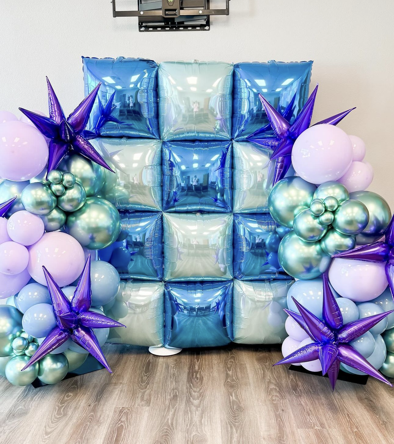 A wall filled with blue and purple balloons and stars.