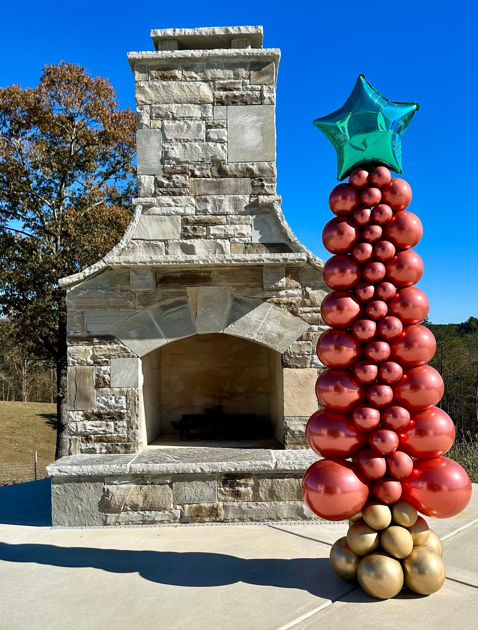 A christmas tree made of balloons is in front of a fireplace.