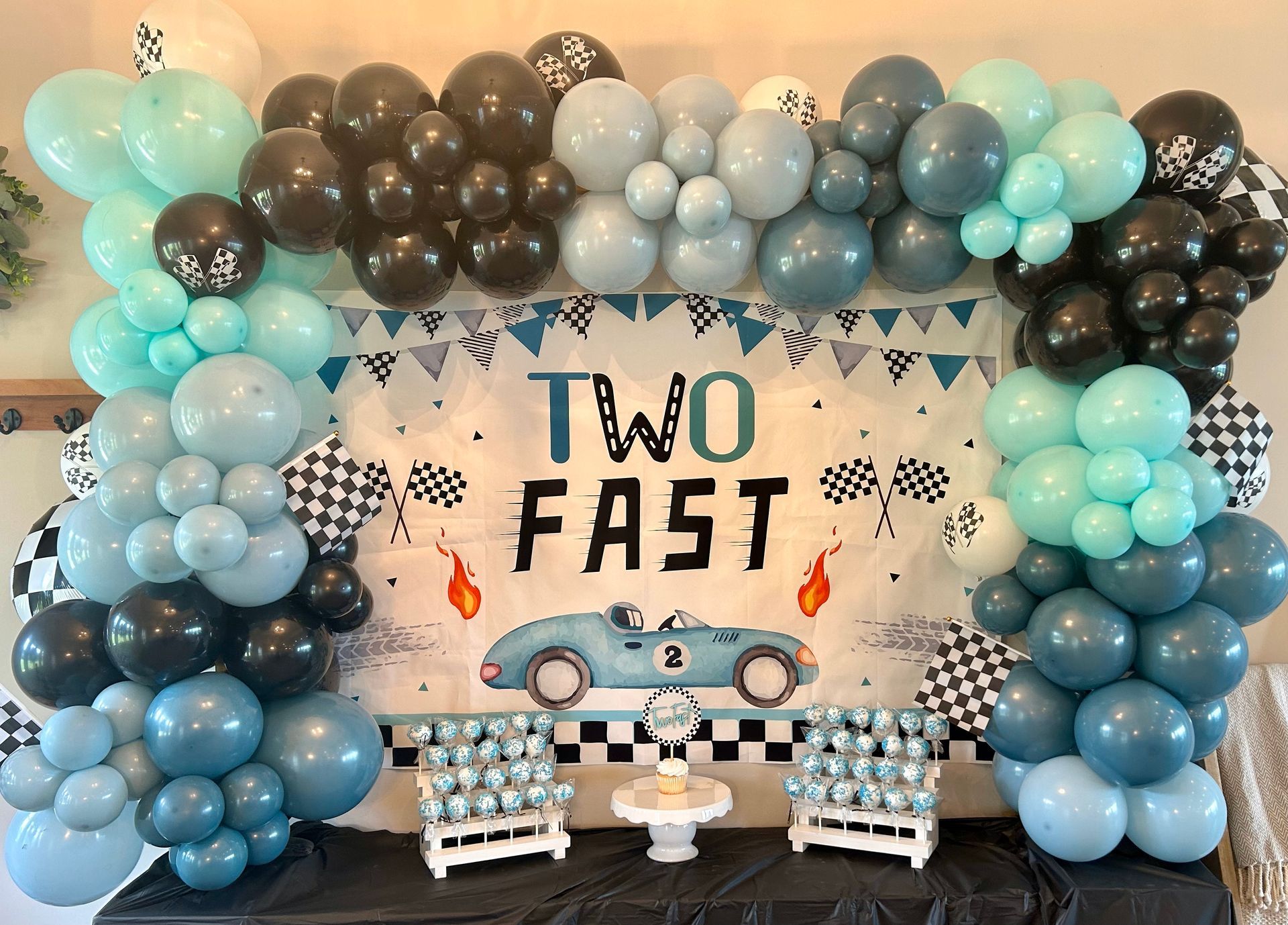 A two fast birthday party with balloons and a cake on a table.