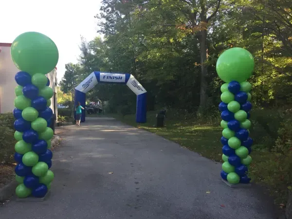 A blue and green balloon archway is surrounded by blue and green balloons.
