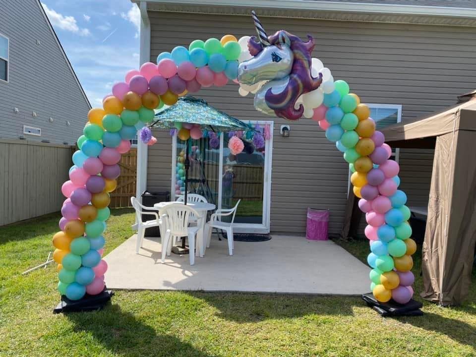 A balloon arch with a unicorn balloon in the middle of it.