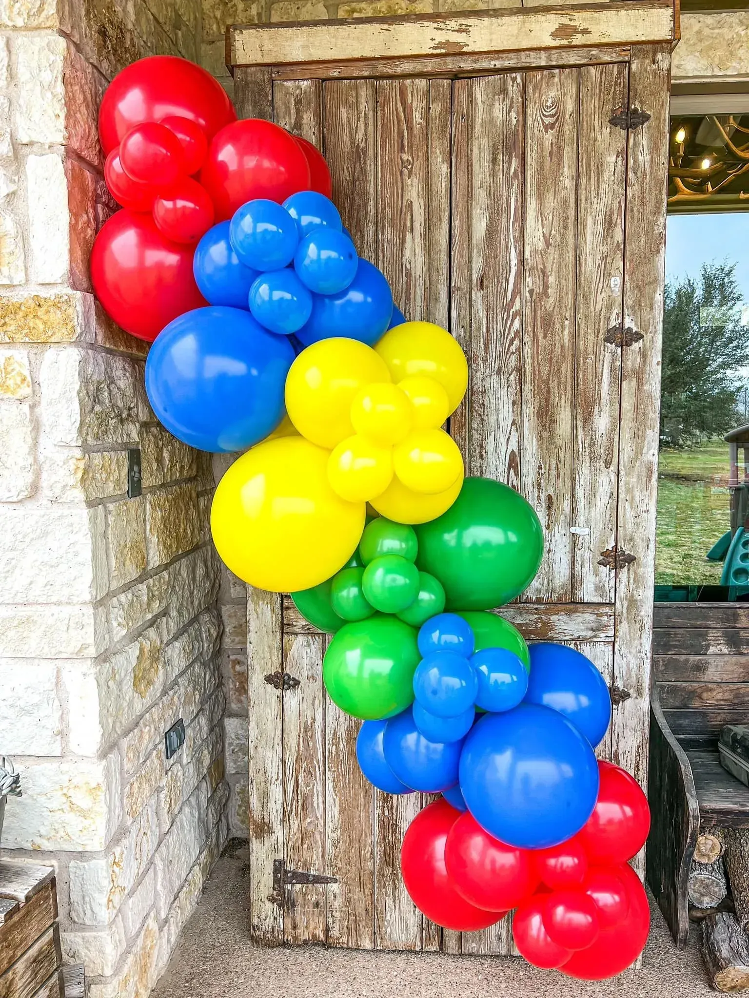 A bunch of colorful balloons are hanging on a wooden door.