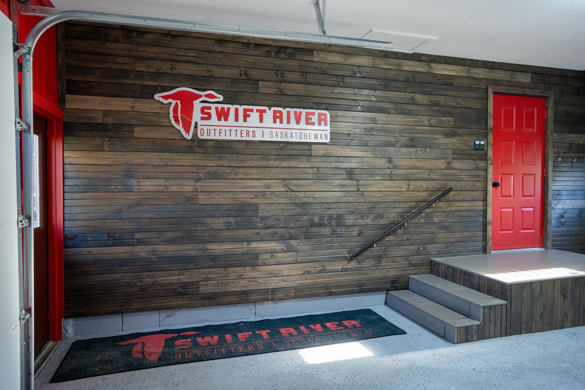 A garage with a wooden wall and a red door.