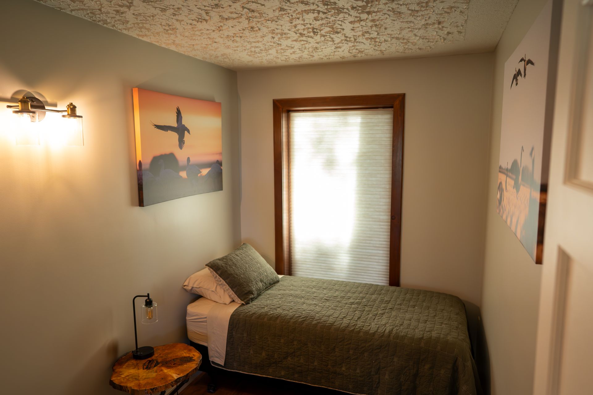 A bedroom with a single bed and a painting on the wall.