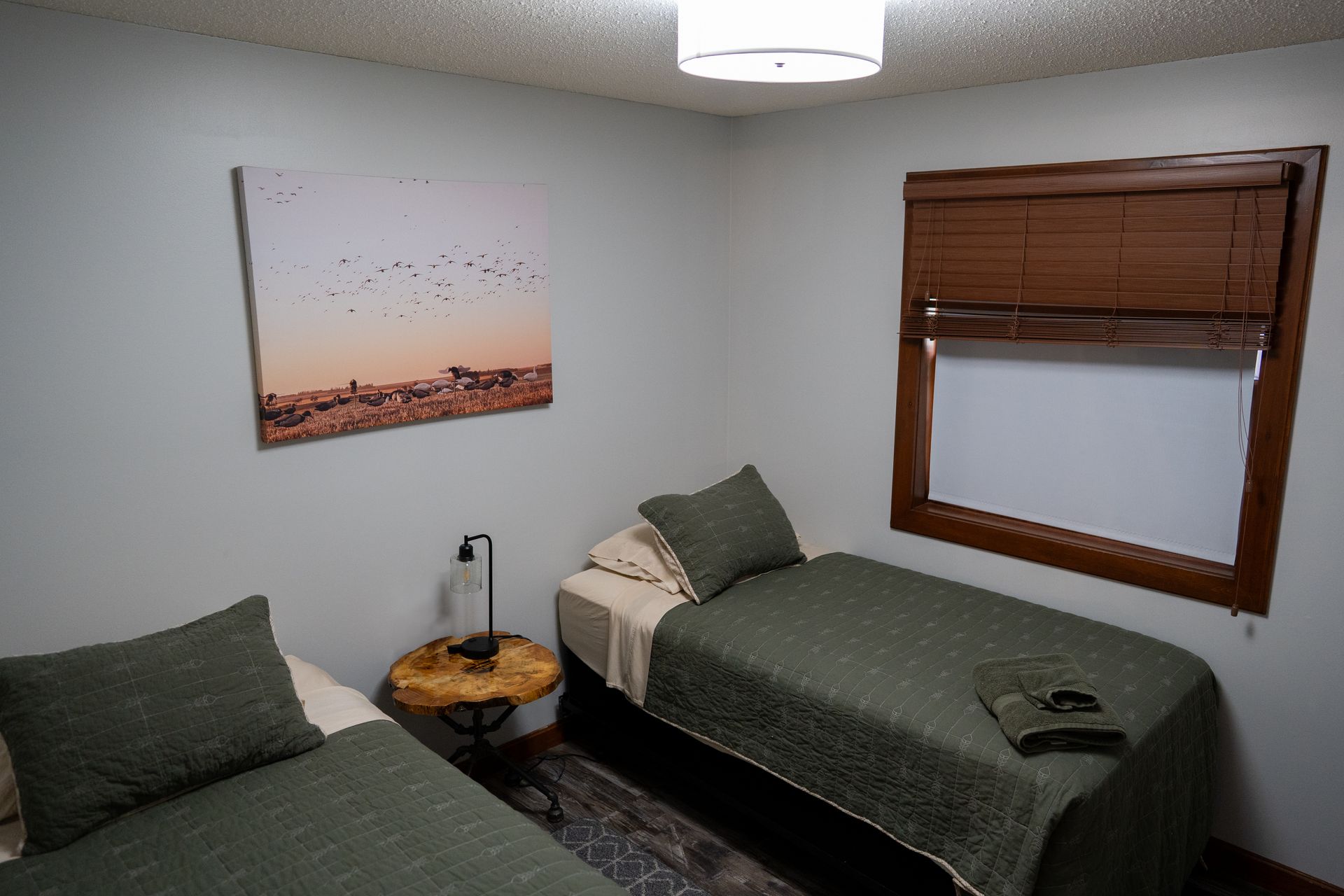 A bedroom with two beds and a painting on the wall