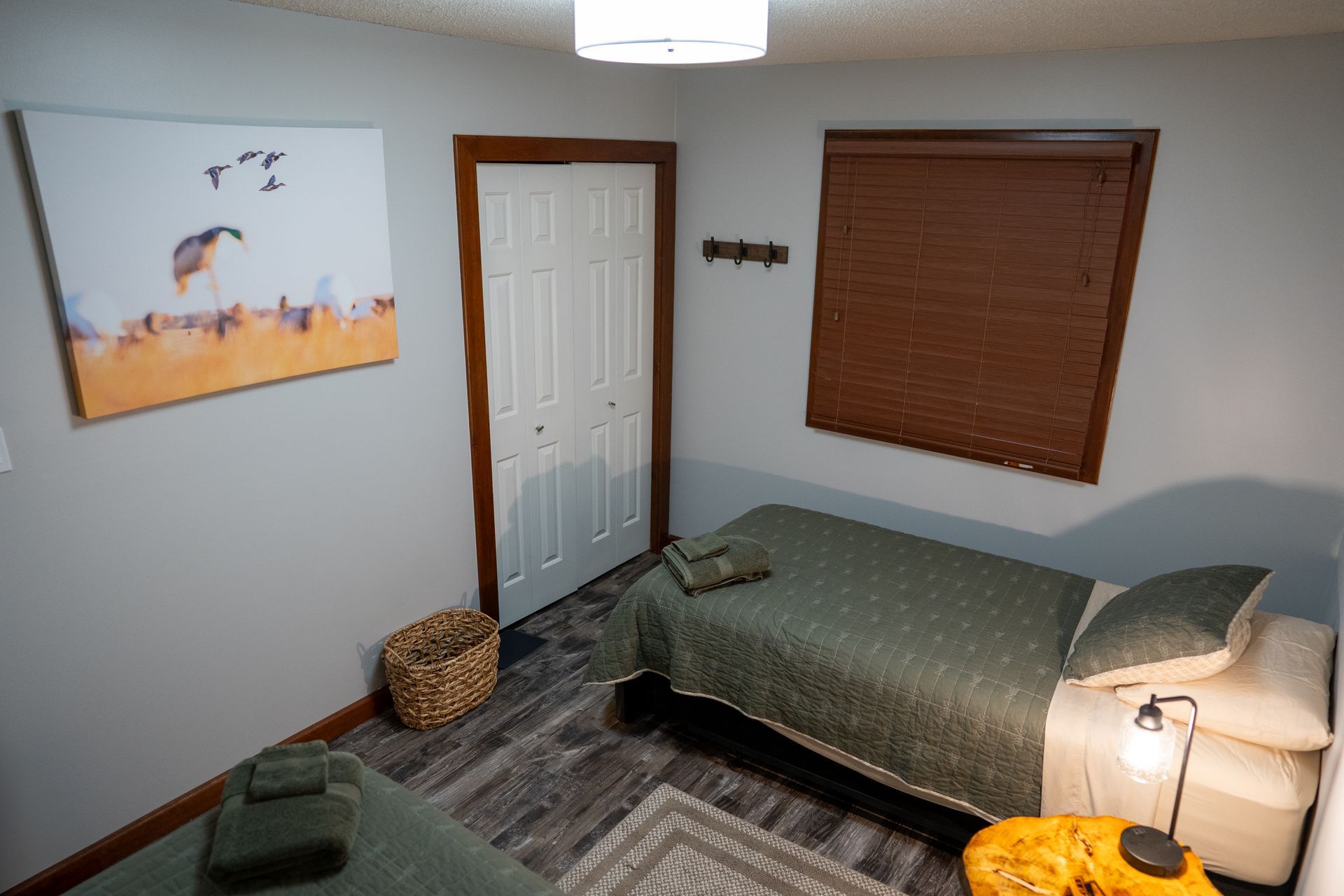 A bedroom with two beds and a painting on the wall.
