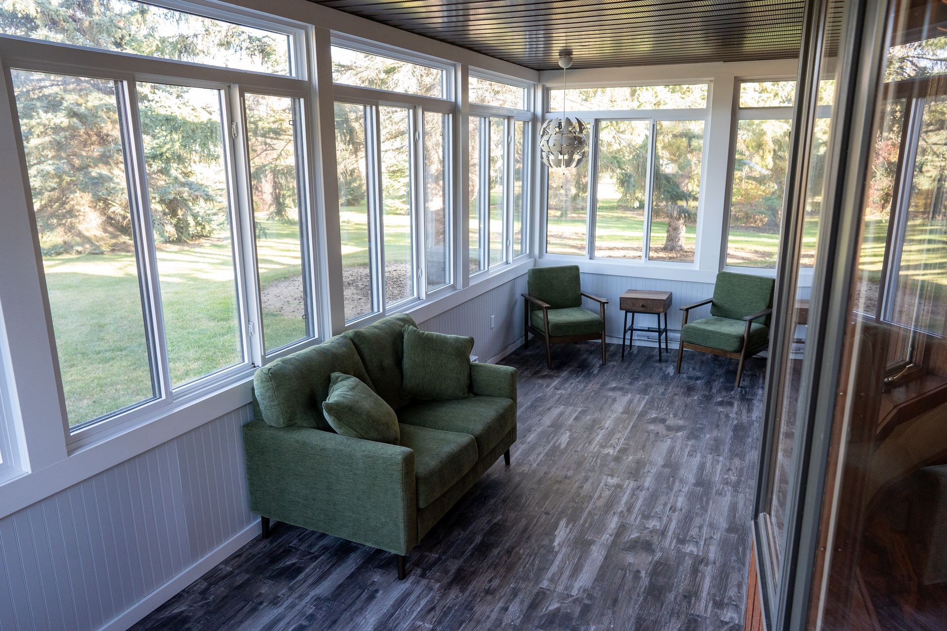 A living room with a couch , chairs , and lots of windows.