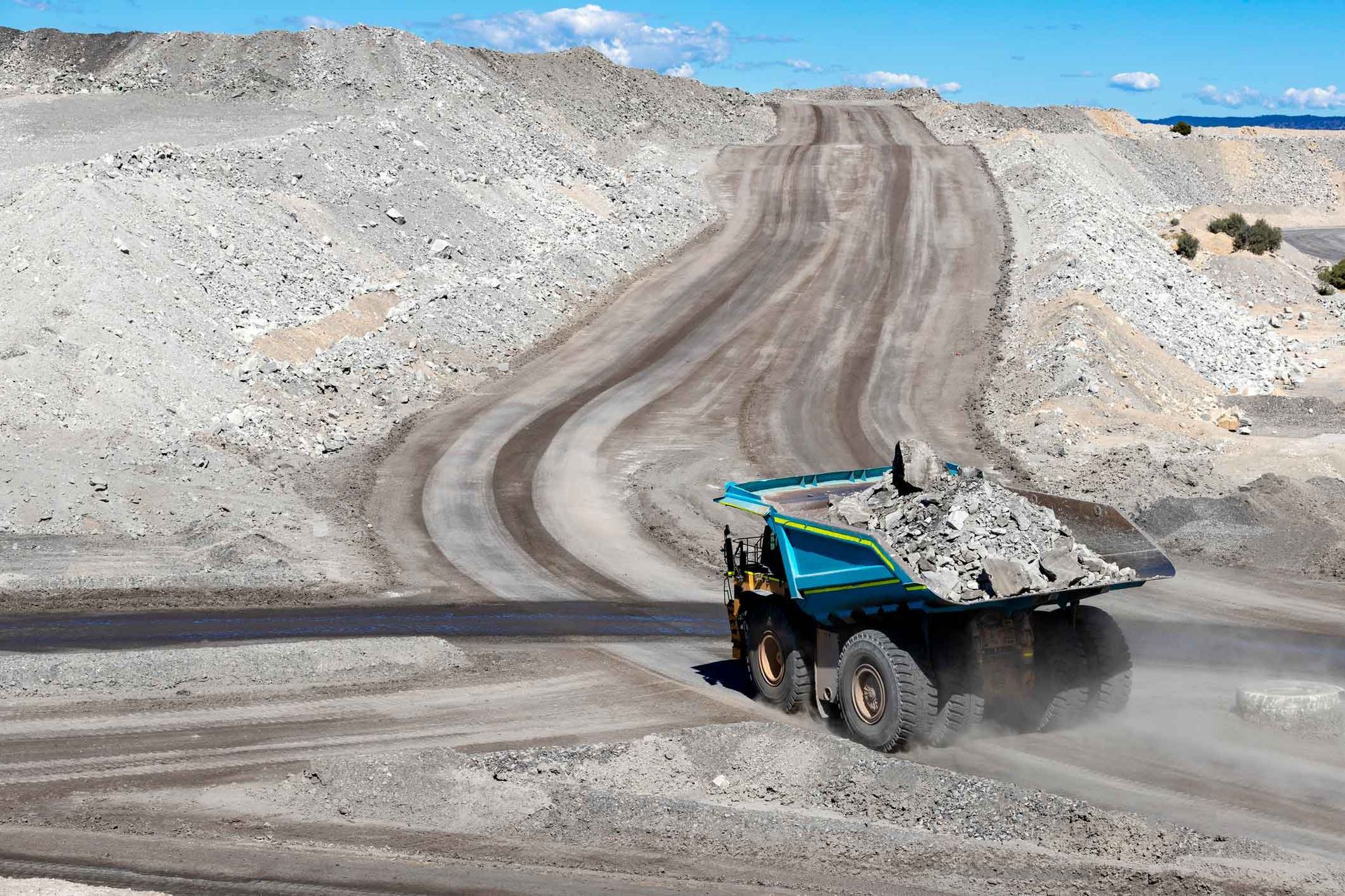 A dump truck is driving down a dirt road.
