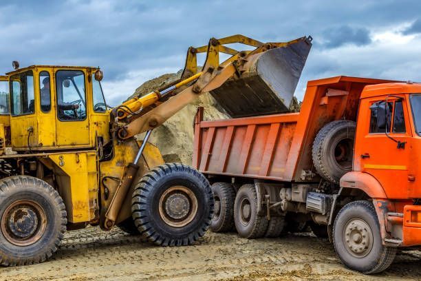 A bulldozer is loading dirt into a dump truck.