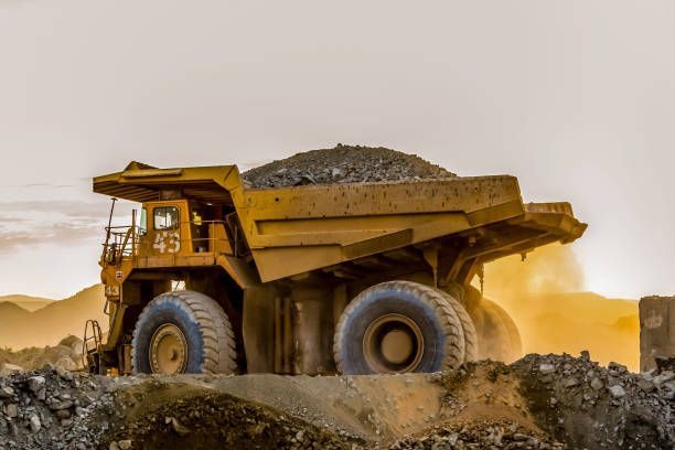 A large dump truck is driving through a dirt field.