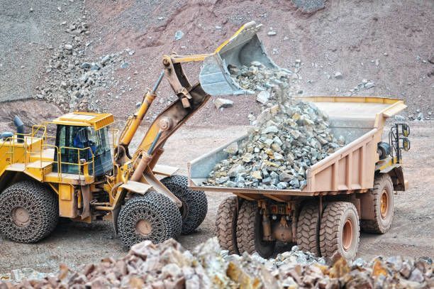 A bulldozer is loading rocks into a dump truck.