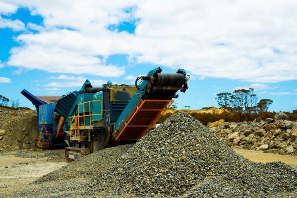 A large pile of rocks is being processed by a machine in a quarry.