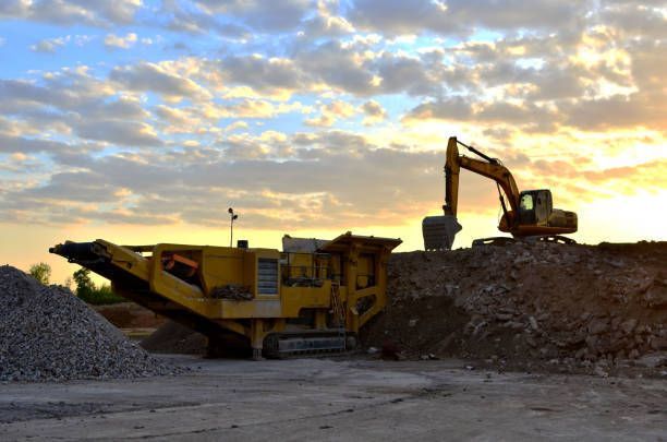 A yellow excavator is digging in a pile of dirt in a construction site.