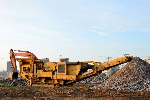 A large yellow machine is sitting on top of a pile of rocks.
