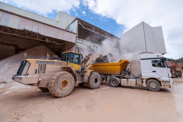 A bulldozer is loading a dump truck with sand.
