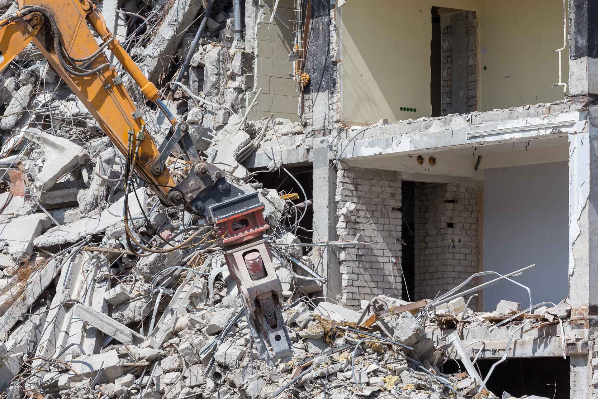 A large pile of rubble is sitting in front of a brick building being demolished.