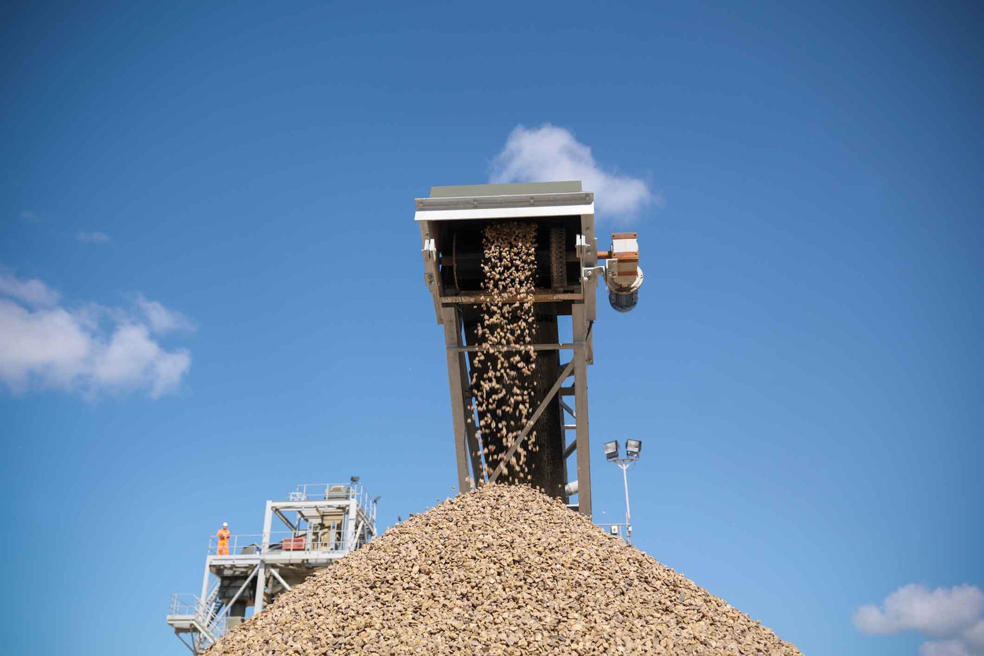 A conveyor belt is carrying a large pile of gravel.