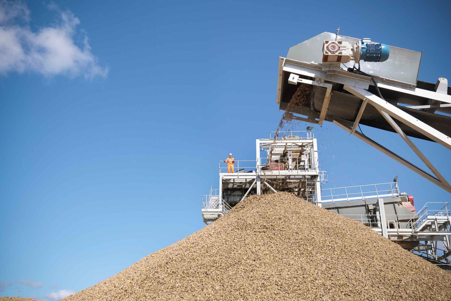 A large pile of gravel is being loaded onto a conveyor belt.