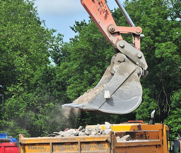 A bulldozer is loading dirt into a dumpster