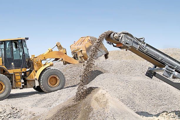 A bulldozer is loading sand into a conveyor belt.