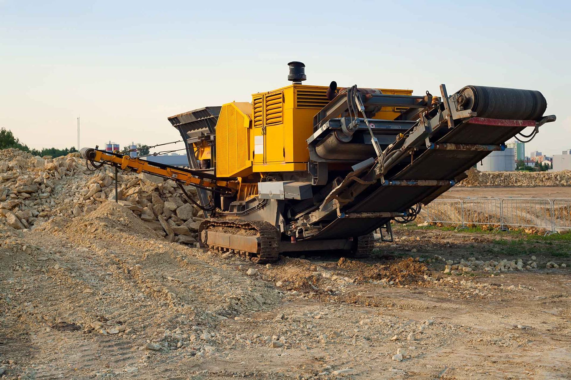 A large yellow machine is sitting in the middle of a dirt field.
