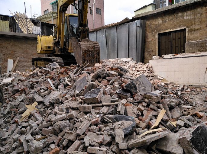 A pile of bricks is being demolished by a bulldozer.