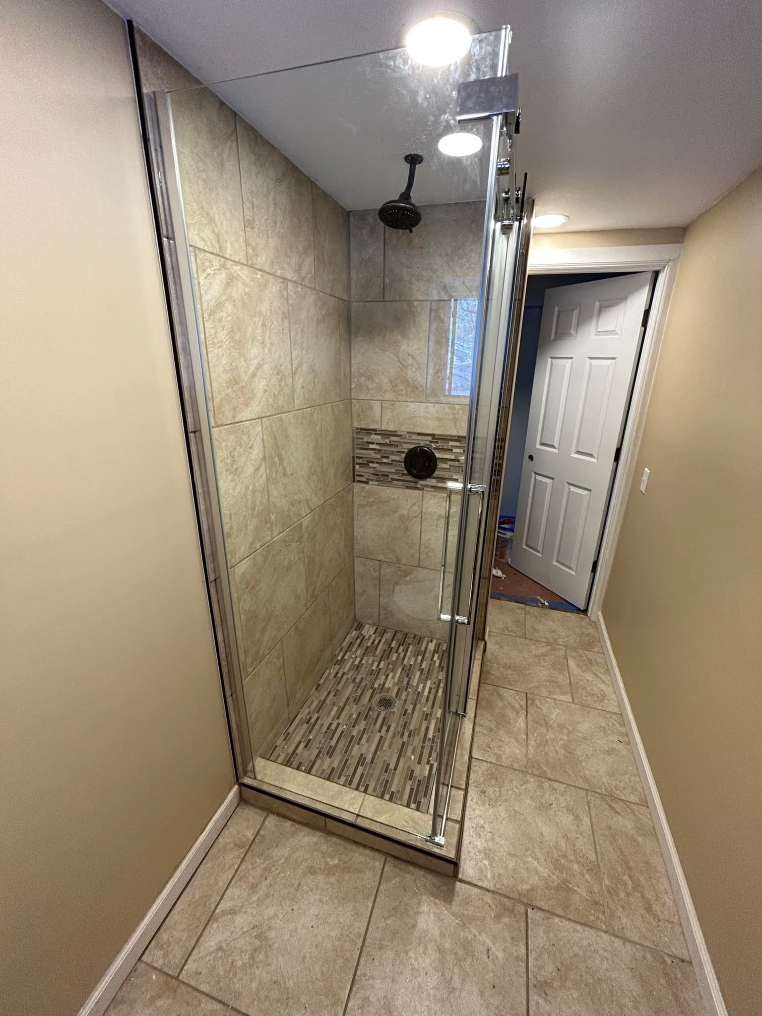 A walk in shower with a glass door in a bathroom.