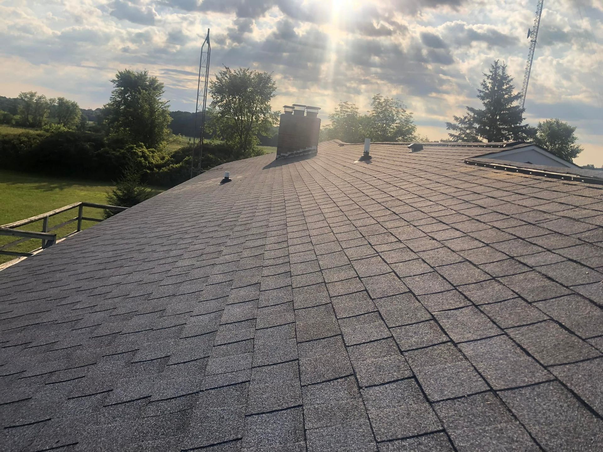 The sun is shining through the clouds on the roof of a house.