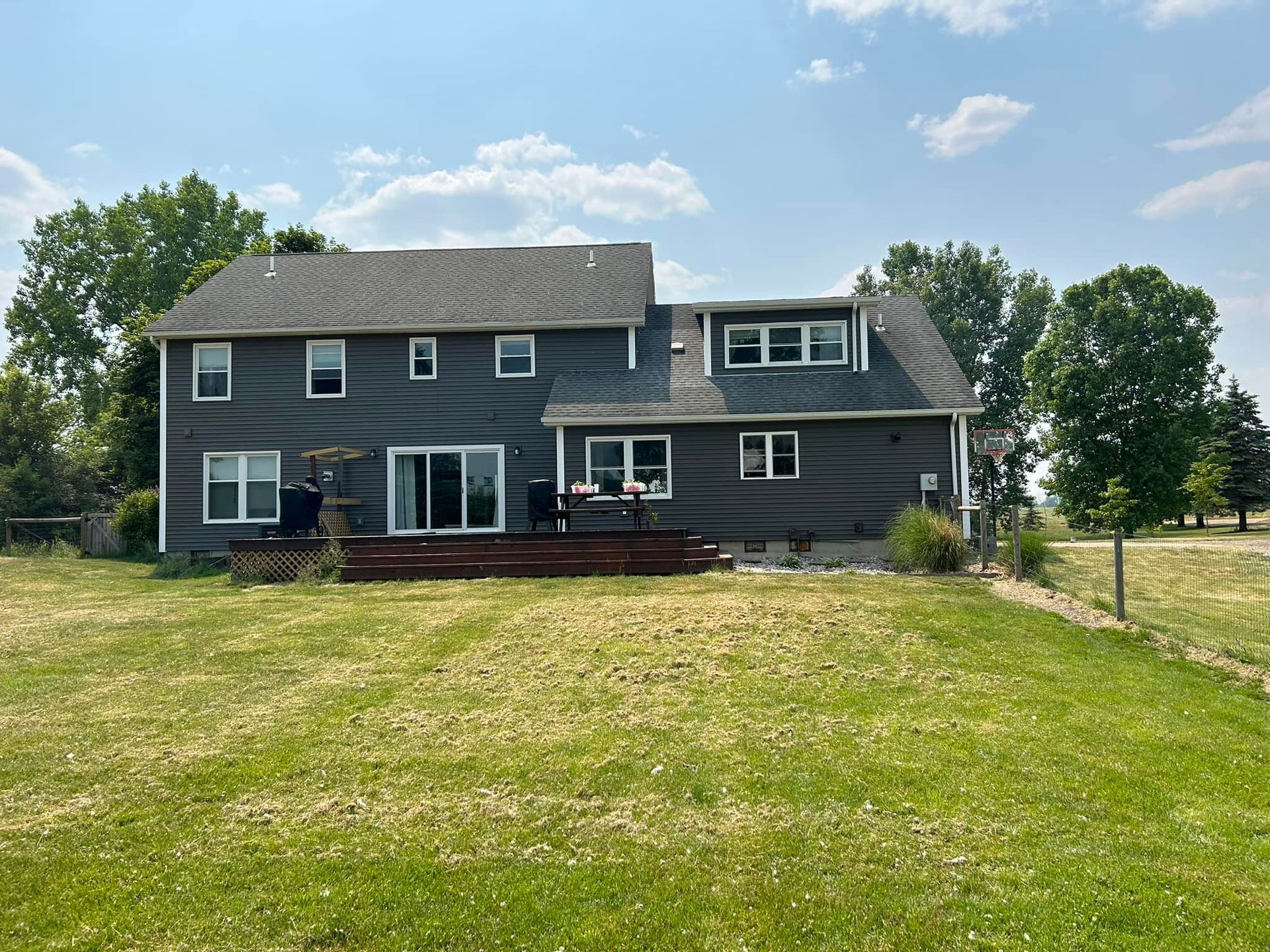 The back of a large house with a large lawn in front of it.
