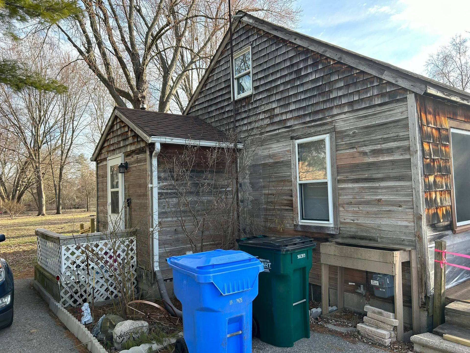 A small wooden house with trash cans in front of it.