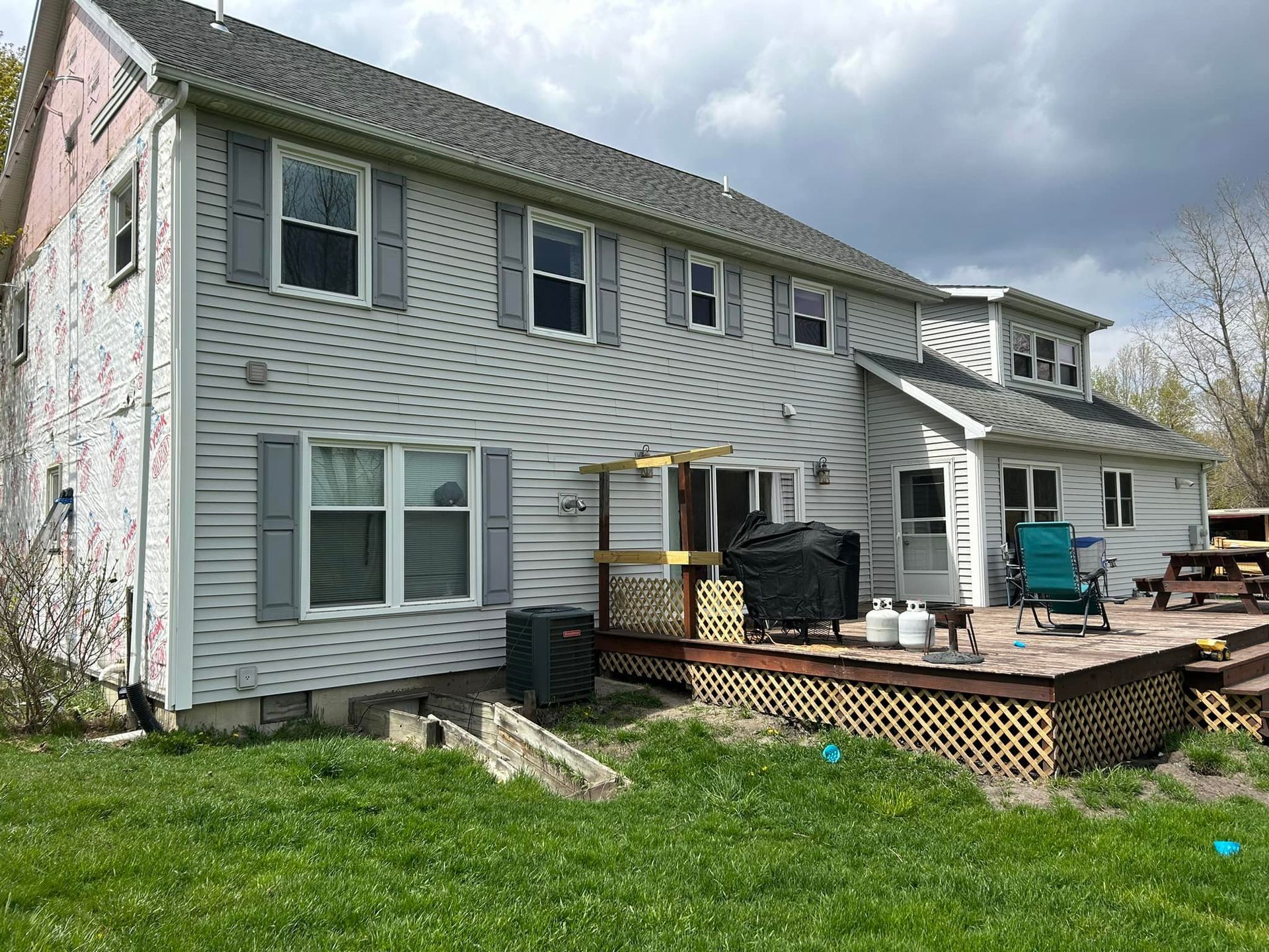 The back of a house with a deck and a picnic table.
