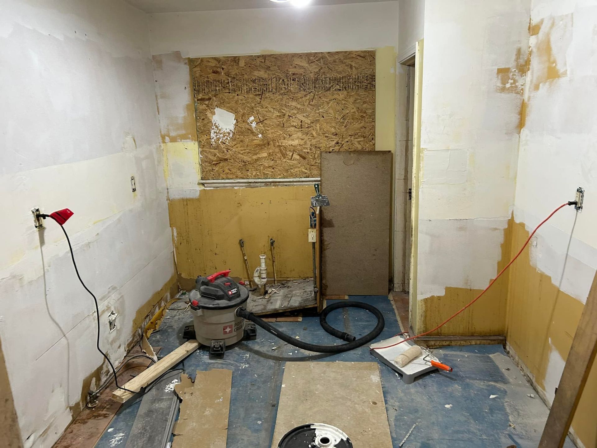 A room with a vacuum cleaner and a lamp on the floor.