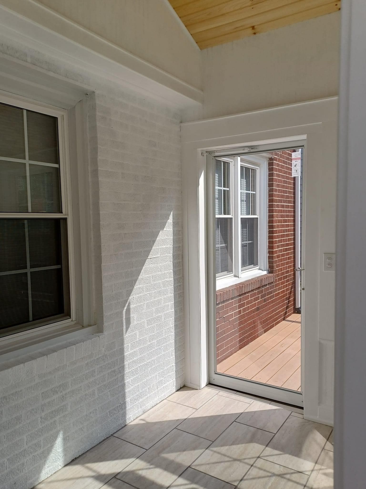An empty room with a brick wall and a sliding glass door