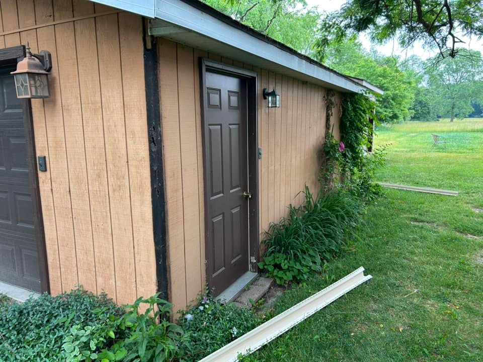 A brown door is on the side of a house.